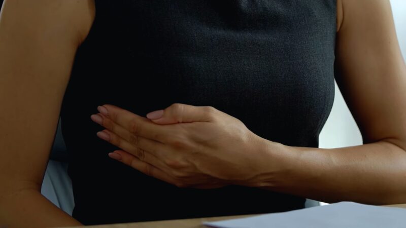 Woman touching her breast, checking for breast cancer